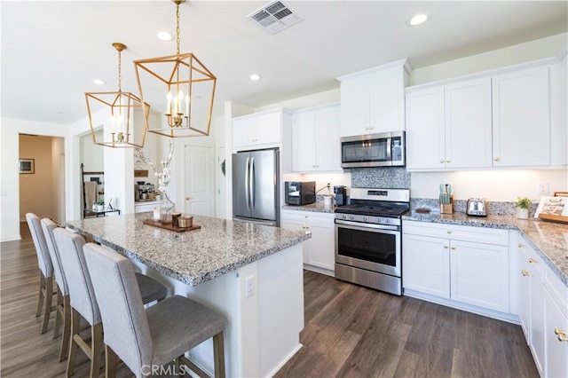 kitchen featuring stainless steel appliances, a kitchen island, visible vents, and white cabinetry