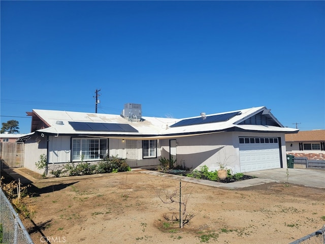 ranch-style home with fence, central air condition unit, concrete driveway, roof mounted solar panels, and an attached garage