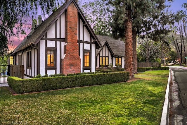 view of side of property with a yard, fence, a chimney, and stucco siding