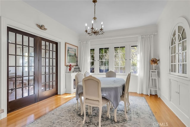 dining space featuring ornamental molding, french doors, an inviting chandelier, and wood finished floors