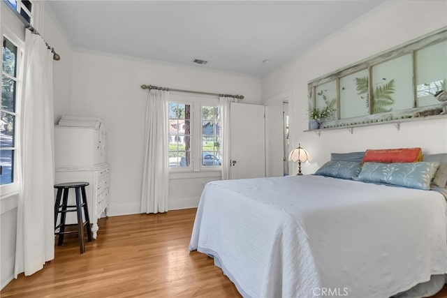 bedroom featuring crown molding, visible vents, and light wood finished floors