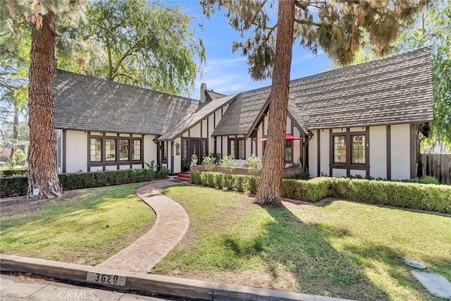 tudor house featuring a front yard and stucco siding