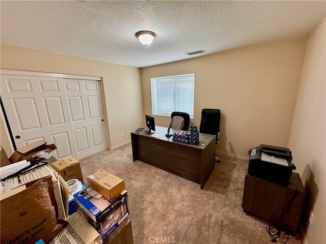 carpeted home office featuring visible vents, a textured ceiling, and baseboards