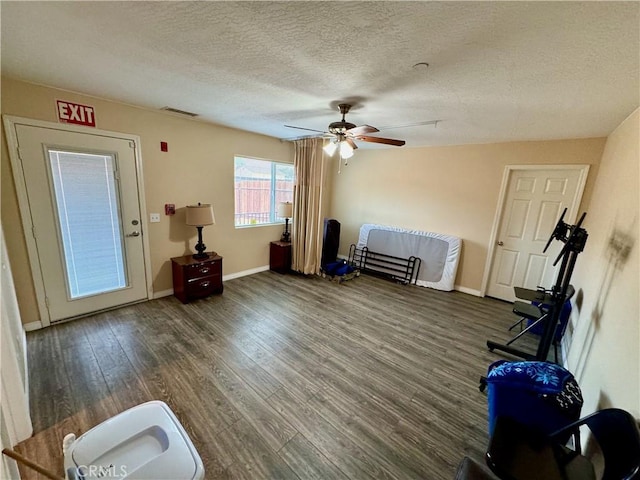 interior space with visible vents, ceiling fan, baseboards, wood finished floors, and a textured ceiling