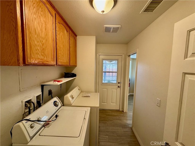 clothes washing area featuring visible vents, cabinet space, and separate washer and dryer