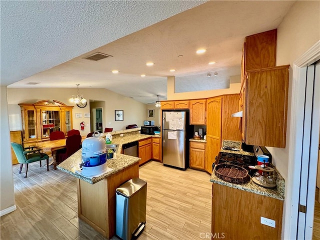 kitchen featuring lofted ceiling, light wood-style flooring, brown cabinets, and stainless steel appliances