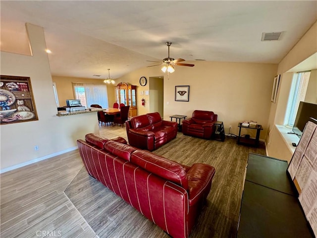 living room with wood finished floors, visible vents, baseboards, vaulted ceiling, and ceiling fan with notable chandelier