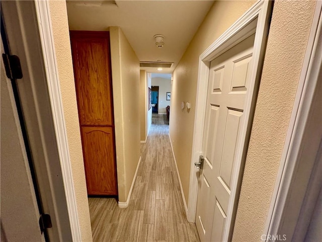 hallway featuring light wood-style flooring and baseboards