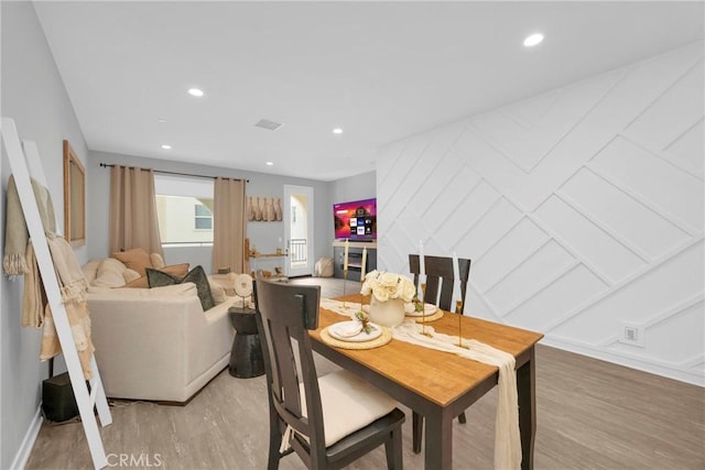 dining area featuring a decorative wall, recessed lighting, and light wood-style floors