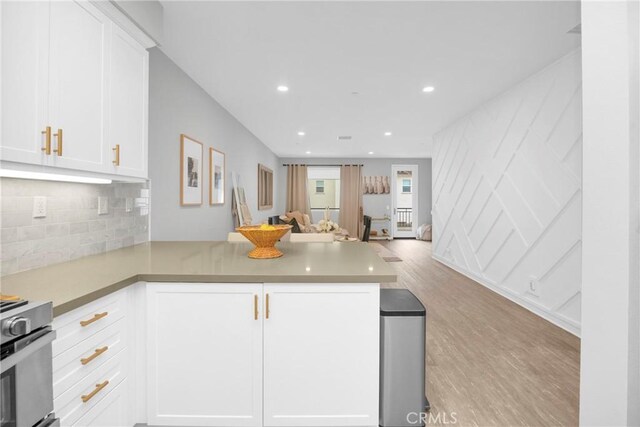 kitchen with stove, open floor plan, a peninsula, and white cabinetry