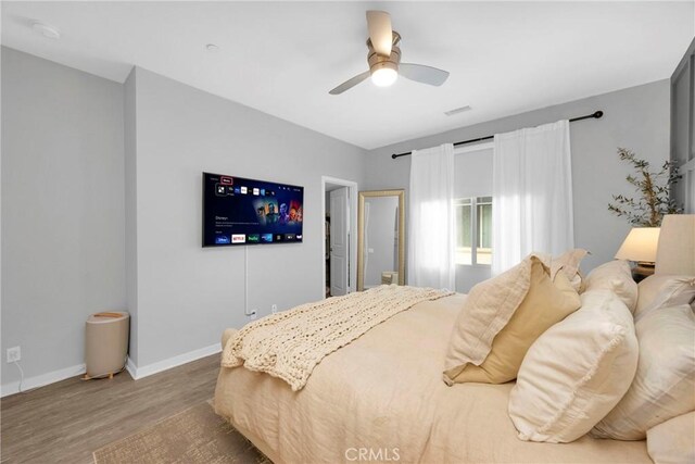 bedroom with ceiling fan, baseboards, and wood finished floors