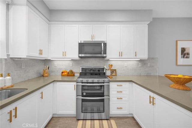 kitchen with light wood-type flooring, decorative backsplash, white cabinets, stainless steel appliances, and a sink