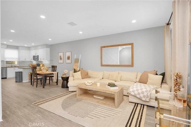 living room with light wood-style flooring, recessed lighting, and visible vents