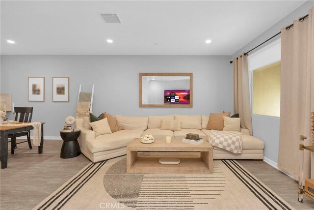 living area with recessed lighting, visible vents, baseboards, and wood finished floors