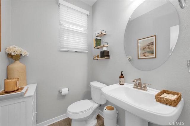 bathroom featuring a sink, baseboards, toilet, and wood finished floors