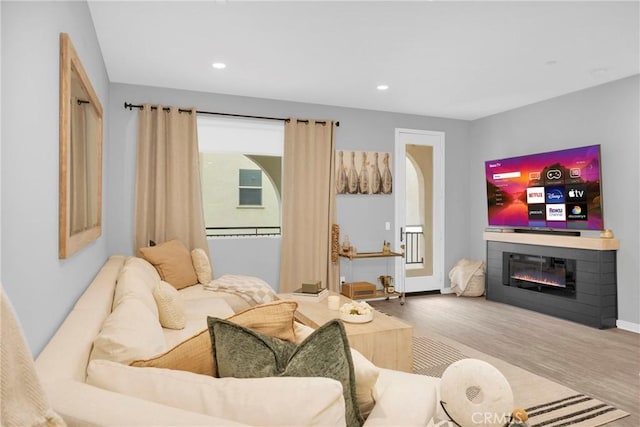 living room with a glass covered fireplace, recessed lighting, and wood finished floors