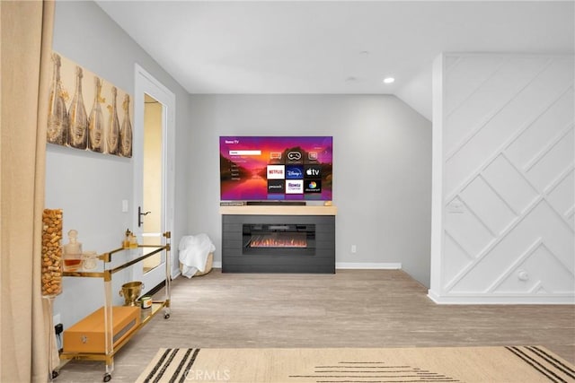 living area featuring a glass covered fireplace, baseboards, wood finished floors, and recessed lighting