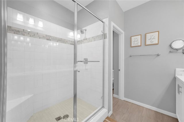 bathroom with a stall shower, vanity, and baseboards