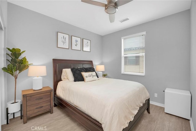 bedroom featuring a ceiling fan, wood finished floors, visible vents, and baseboards