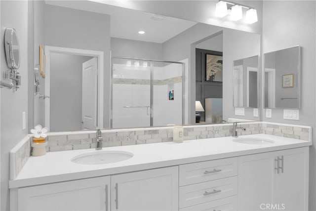 full bath featuring decorative backsplash, double vanity, a stall shower, and a sink