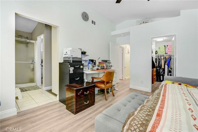 home office with lofted ceiling, light wood-style flooring, baseboards, and visible vents