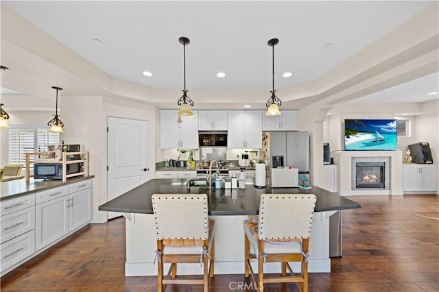 kitchen with a glass covered fireplace, dark countertops, dark wood-style flooring, and stainless steel refrigerator with ice dispenser