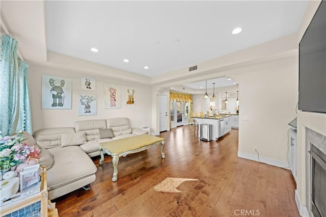 living area with a tray ceiling, hardwood / wood-style flooring, recessed lighting, and visible vents