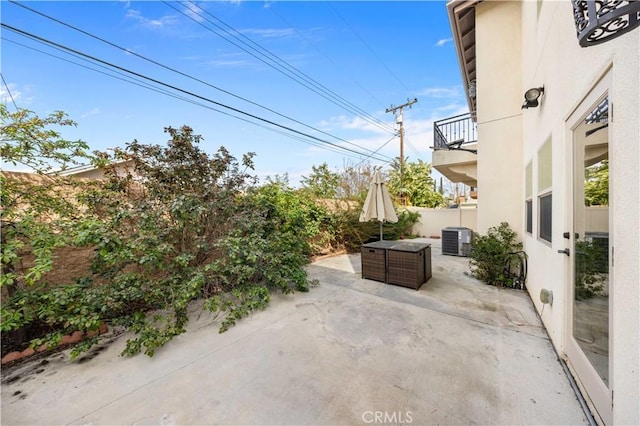 view of patio / terrace with a balcony, central air condition unit, and fence