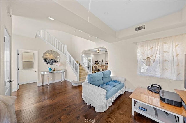 living area featuring arched walkways, visible vents, stairway, and wood-type flooring