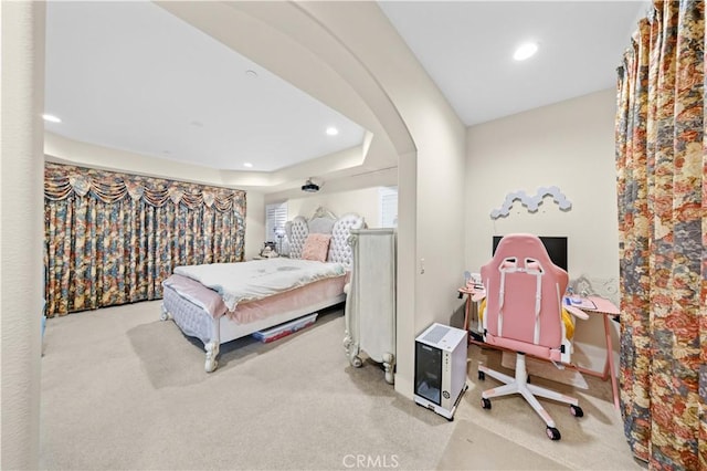 carpeted bedroom featuring a raised ceiling, recessed lighting, and arched walkways