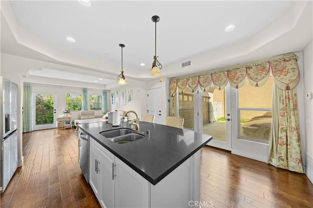 kitchen with visible vents, a sink, dark countertops, a raised ceiling, and dishwasher