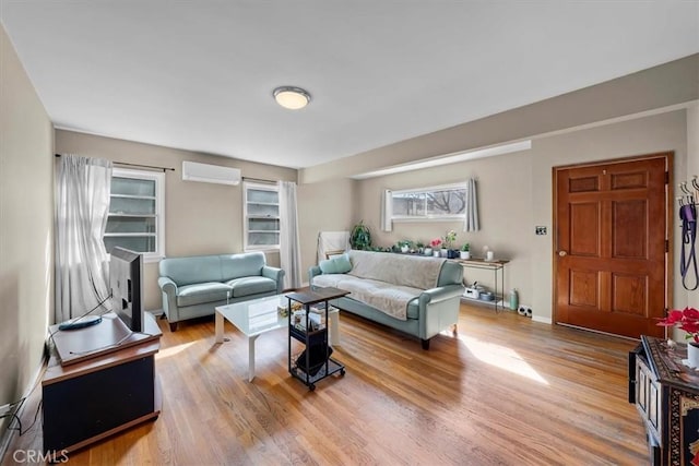 living room with wood finished floors, baseboards, and a wall mounted air conditioner