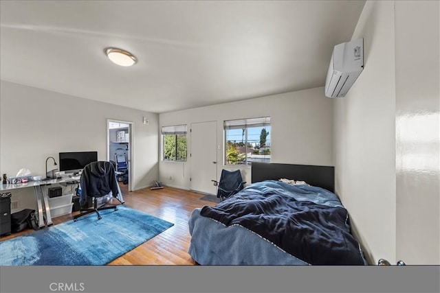 bedroom featuring a wall unit AC and wood finished floors