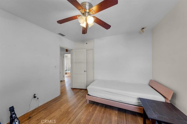 bedroom featuring a ceiling fan, visible vents, and light wood finished floors