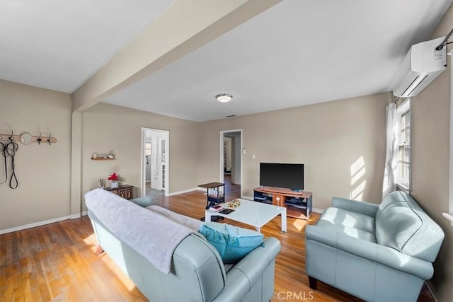 living area with baseboards, light wood-style floors, beam ceiling, and a wall mounted AC