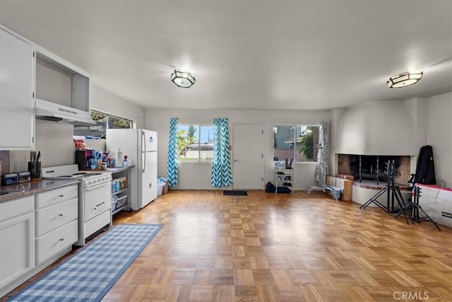 kitchen featuring white appliances, white cabinets, open floor plan, and under cabinet range hood