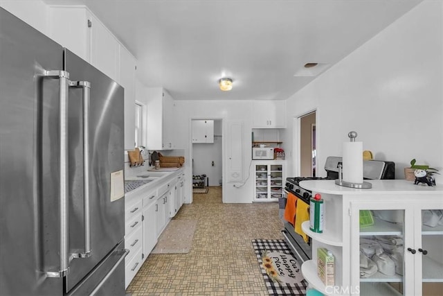 kitchen featuring stove, white cabinetry, high quality fridge, light countertops, and white microwave