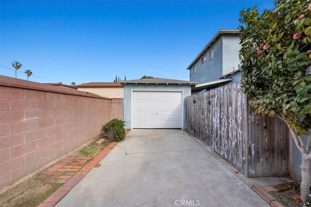 garage with concrete driveway and fence