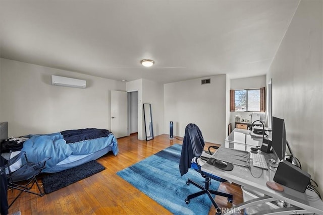 office with hardwood / wood-style flooring, visible vents, and a wall mounted AC