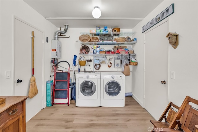 clothes washing area with laundry area, light wood-type flooring, tankless water heater, and washing machine and clothes dryer