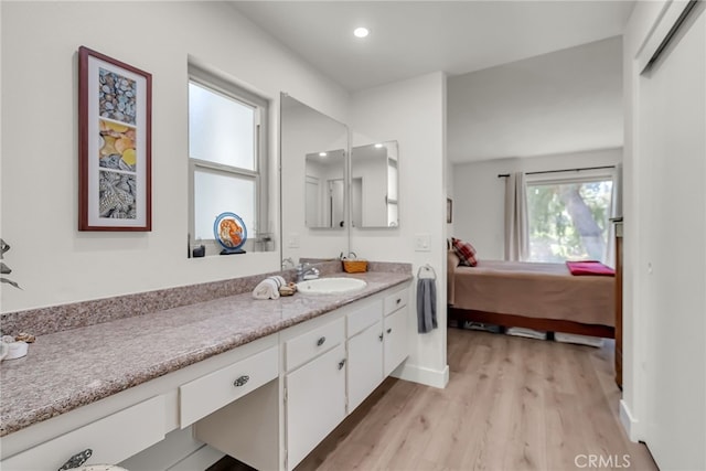 ensuite bathroom featuring connected bathroom, baseboards, recessed lighting, wood finished floors, and vanity