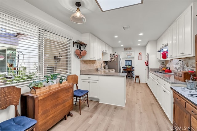 kitchen featuring a sink, light wood-type flooring, white cabinetry, and freestanding refrigerator