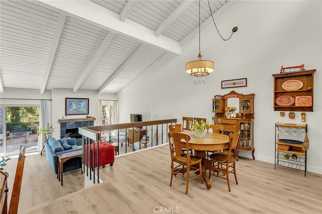 dining area featuring beam ceiling, light wood-style flooring, and a fireplace