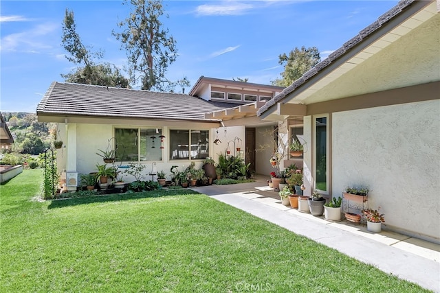 exterior space featuring a lawn, a tiled roof, and stucco siding