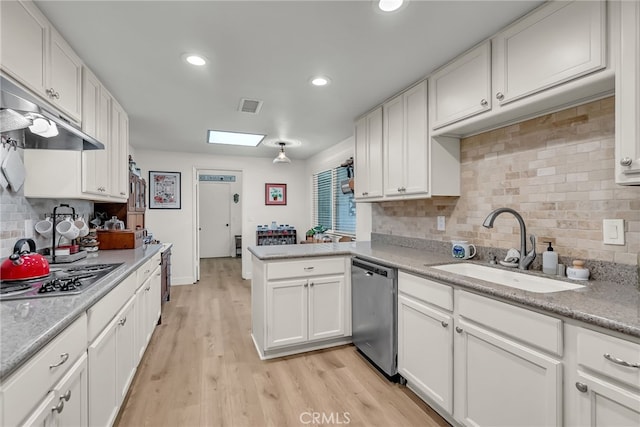 kitchen featuring visible vents, a sink, light wood-style floors, appliances with stainless steel finishes, and a peninsula