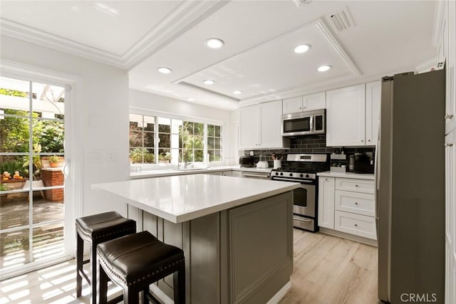 kitchen with white cabinetry, appliances with stainless steel finishes, a breakfast bar area, and light countertops