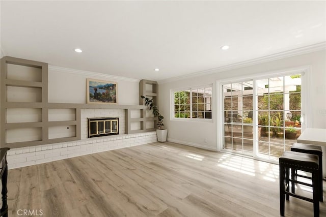 unfurnished living room with a fireplace, crown molding, built in shelves, and wood finished floors