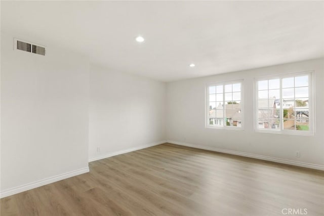 empty room featuring recessed lighting, visible vents, light wood-style flooring, and baseboards