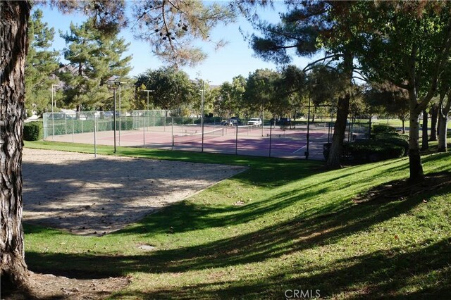 view of property's community featuring a tennis court, fence, and a lawn