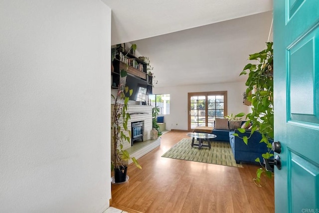 foyer with a glass covered fireplace, wood finished floors, and baseboards